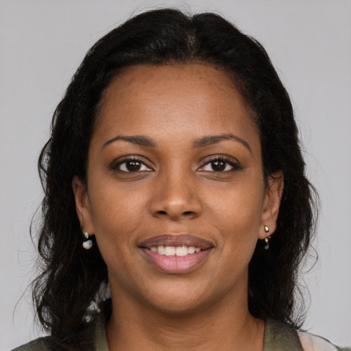 Joyful black young-adult female with long  brown hair and brown eyes