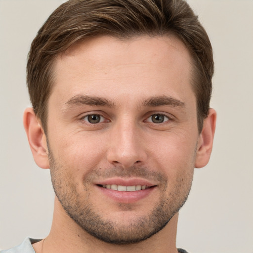 Joyful white young-adult male with short  brown hair and grey eyes