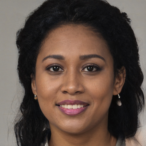 Joyful black young-adult female with long  brown hair and brown eyes