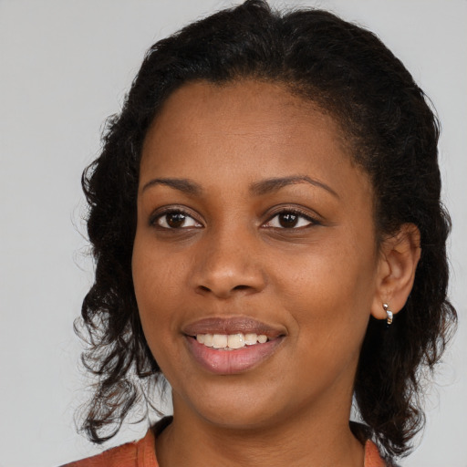 Joyful black young-adult female with long  brown hair and brown eyes