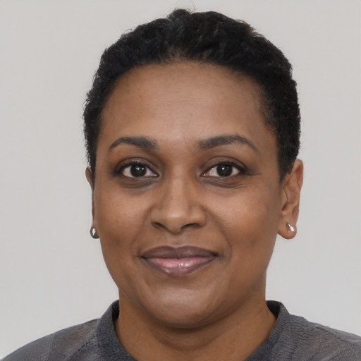 Joyful black adult female with short  black hair and brown eyes