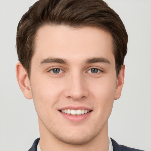 Joyful white young-adult male with short  brown hair and grey eyes