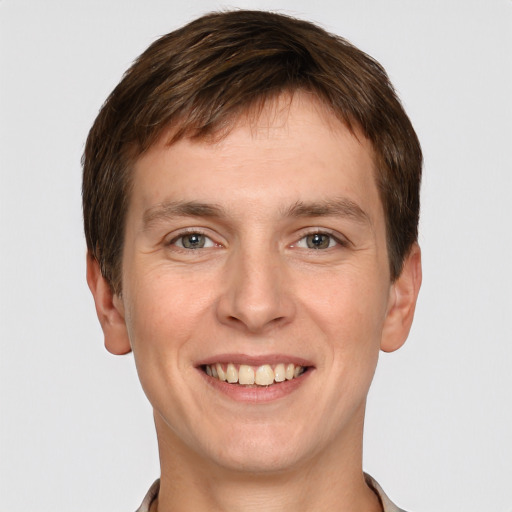 Joyful white young-adult male with short  brown hair and grey eyes