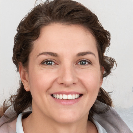 Joyful white young-adult female with medium  brown hair and grey eyes