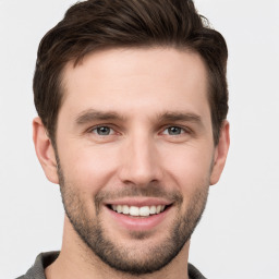 Joyful white young-adult male with short  brown hair and grey eyes