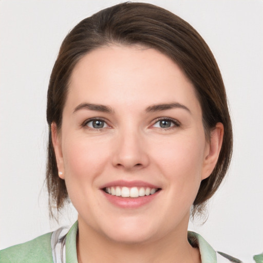 Joyful white young-adult female with medium  brown hair and grey eyes