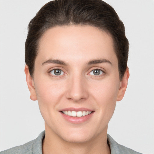 Joyful white young-adult female with short  brown hair and grey eyes