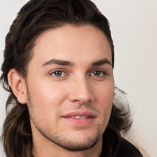 Joyful white young-adult male with long  brown hair and brown eyes