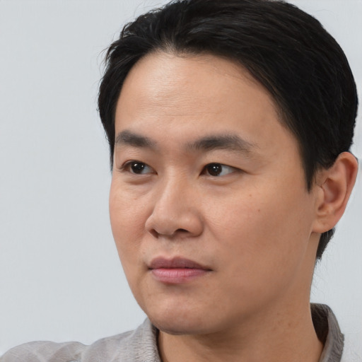 Joyful asian young-adult male with short  black hair and brown eyes