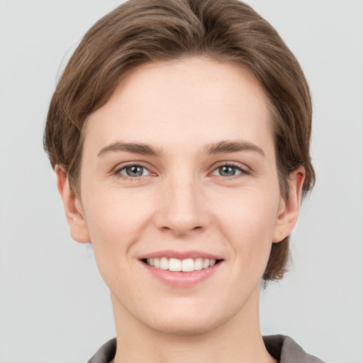 Joyful white young-adult female with short  brown hair and grey eyes