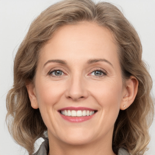 Joyful white adult female with medium  brown hair and grey eyes