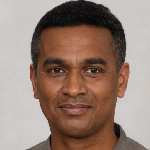 Joyful black adult male with short  black hair and brown eyes