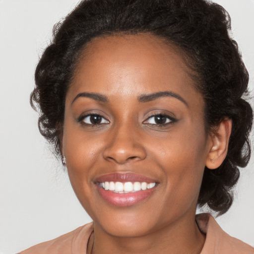 Joyful black young-adult female with long  brown hair and brown eyes