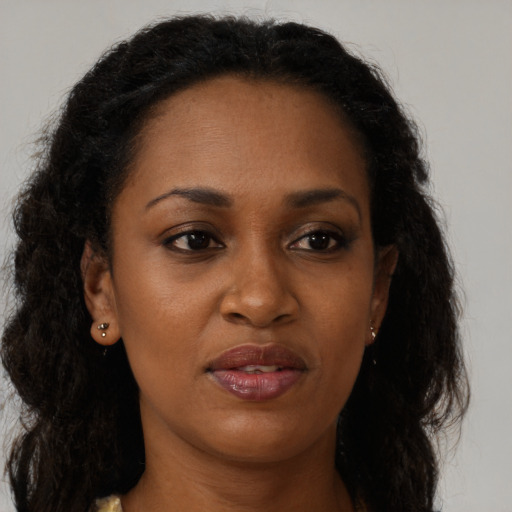 Joyful black young-adult female with long  brown hair and brown eyes