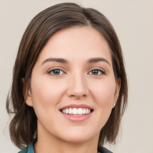 Joyful white young-adult female with medium  brown hair and grey eyes