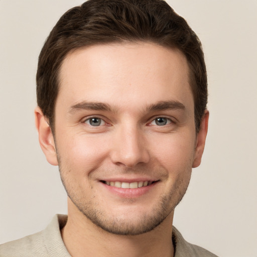 Joyful white young-adult male with short  brown hair and grey eyes