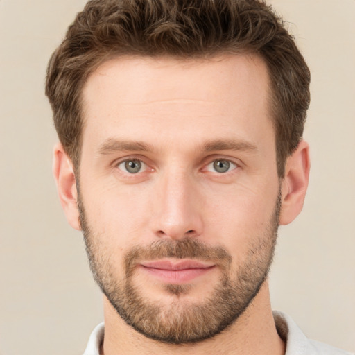 Joyful white young-adult male with short  brown hair and grey eyes