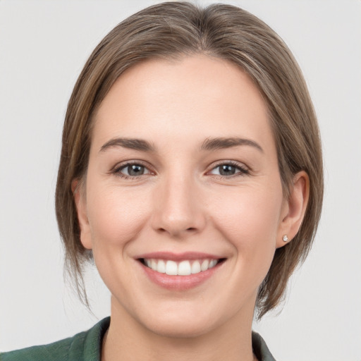 Joyful white young-adult female with medium  brown hair and grey eyes