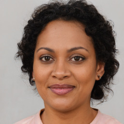 Joyful black young-adult female with long  brown hair and brown eyes