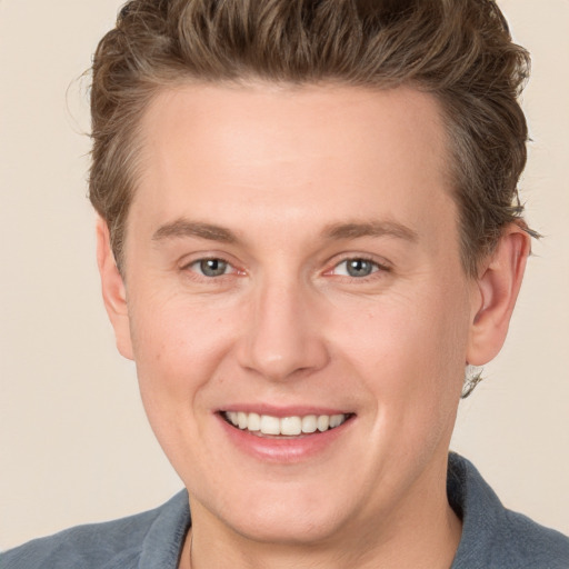 Joyful white young-adult male with short  brown hair and grey eyes