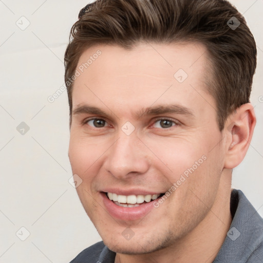 Joyful white young-adult male with short  brown hair and grey eyes