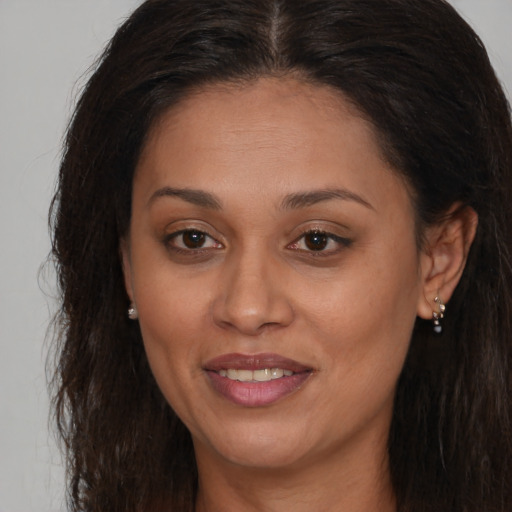 Joyful black young-adult female with long  brown hair and brown eyes