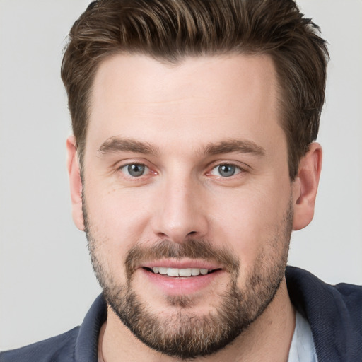 Joyful white young-adult male with short  brown hair and grey eyes