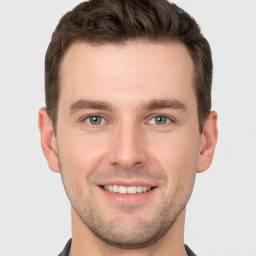 Joyful white young-adult male with short  brown hair and grey eyes