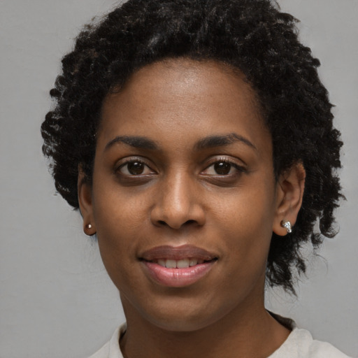 Joyful black young-adult female with short  black hair and brown eyes
