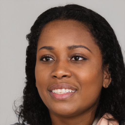 Joyful black young-adult female with long  black hair and brown eyes