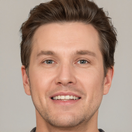 Joyful white young-adult male with short  brown hair and grey eyes