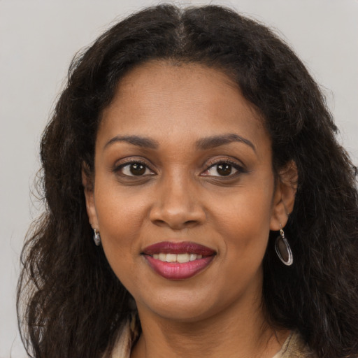 Joyful black young-adult female with long  brown hair and brown eyes