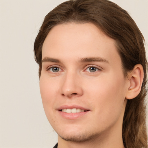 Joyful white young-adult male with long  brown hair and brown eyes