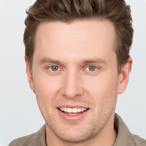 Joyful white young-adult male with short  brown hair and grey eyes