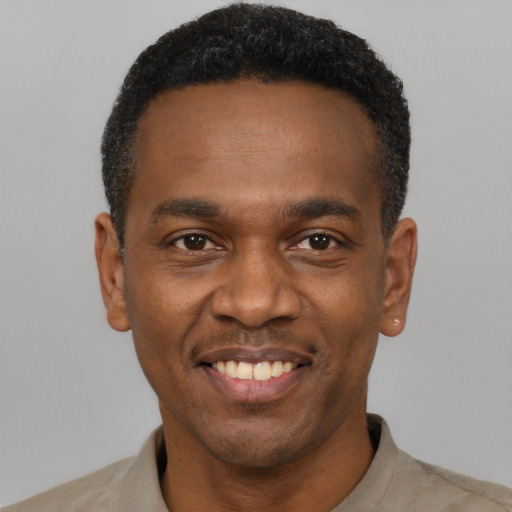 Joyful black young-adult male with short  black hair and brown eyes
