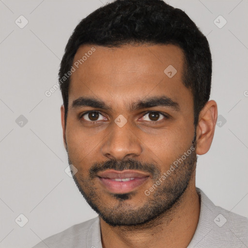 Joyful black young-adult male with short  black hair and brown eyes