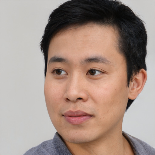 Joyful asian young-adult male with short  black hair and brown eyes