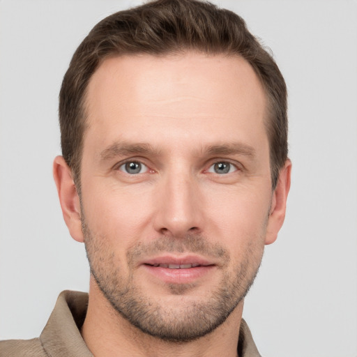 Joyful white young-adult male with short  brown hair and grey eyes