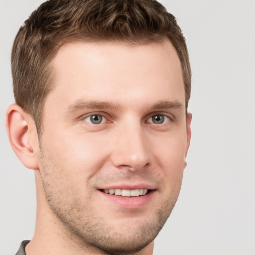 Joyful white young-adult male with short  brown hair and grey eyes