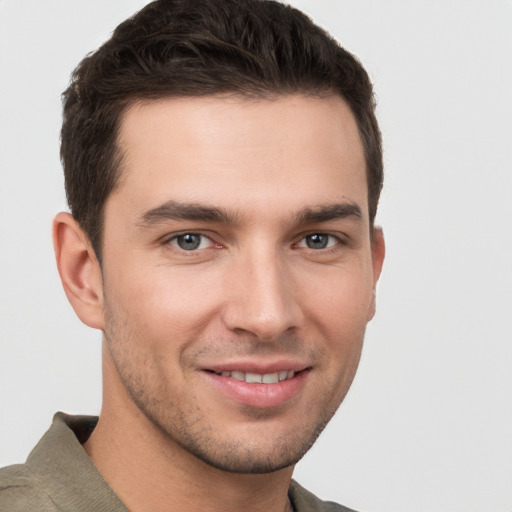 Joyful white young-adult male with short  brown hair and grey eyes