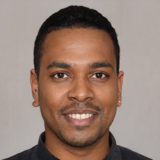 Joyful black young-adult male with short  black hair and brown eyes