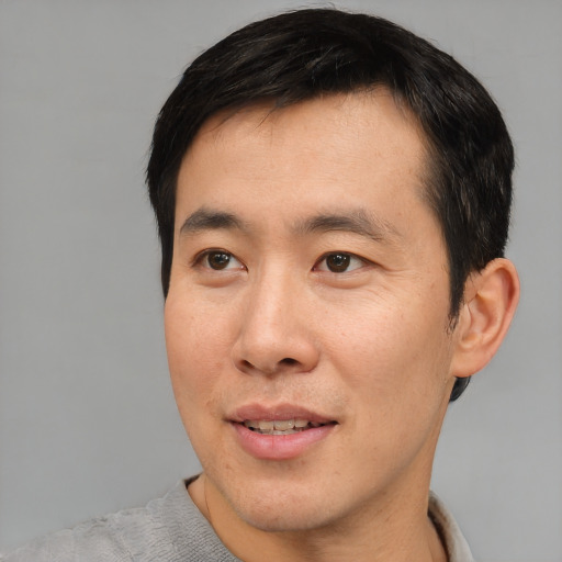 Joyful asian young-adult male with short  black hair and brown eyes