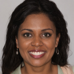 Joyful black young-adult female with long  brown hair and brown eyes