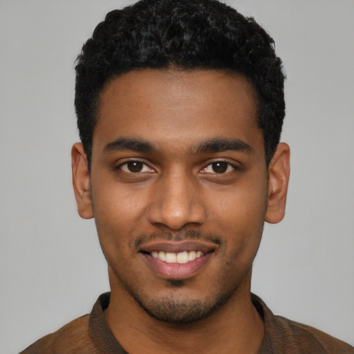 Joyful black young-adult male with short  black hair and brown eyes