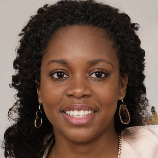 Joyful black young-adult female with long  brown hair and brown eyes