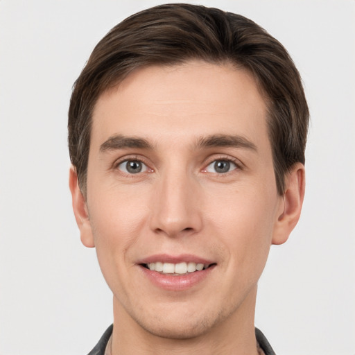 Joyful white young-adult male with short  brown hair and grey eyes