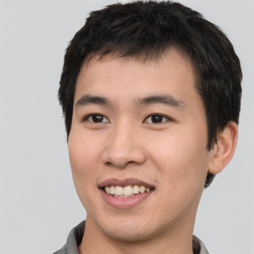 Joyful asian young-adult male with short  brown hair and brown eyes