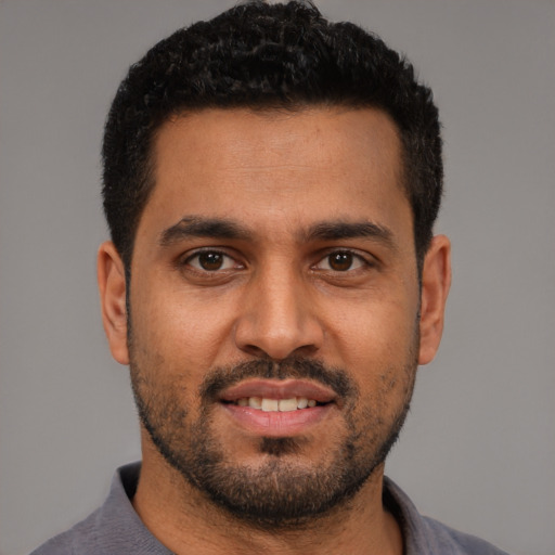 Joyful latino young-adult male with short  black hair and brown eyes