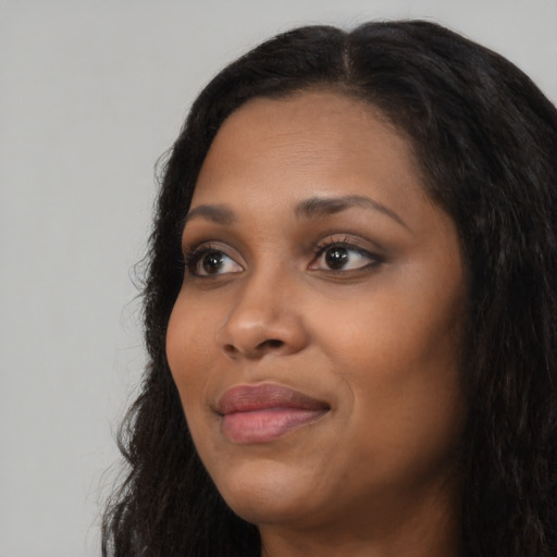 Joyful black adult female with long  black hair and brown eyes
