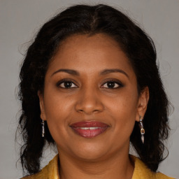 Joyful black adult female with long  brown hair and brown eyes